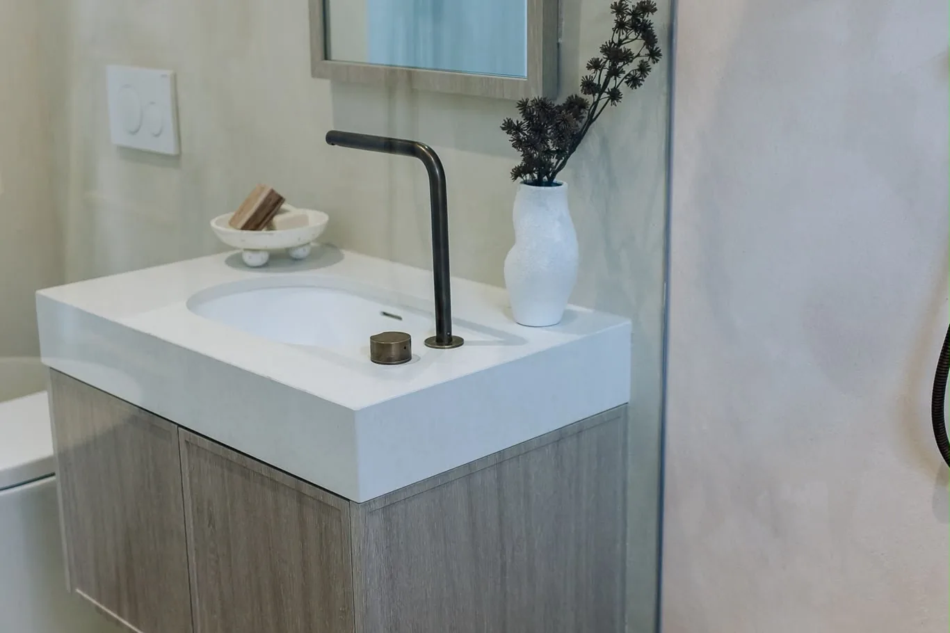 White basin on a floating timber-look vanity against pale microcement walls