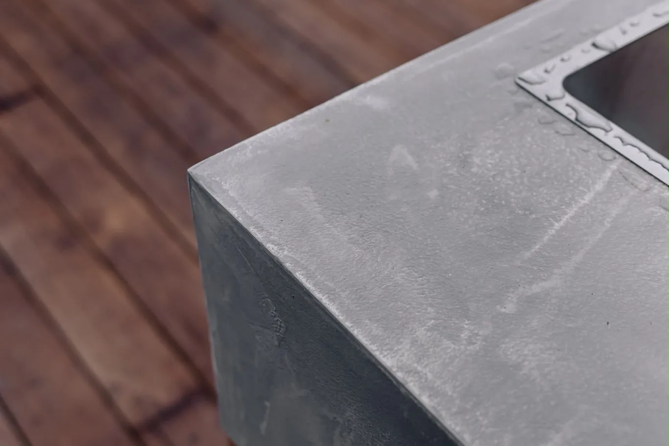 Close view of the corner of a grey microcement benchtop with a sink set into it